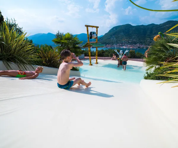 Kids playing on a water slide with a mountain view.