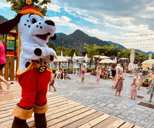 Spotty in red pants on stage, mountains and crowd in background.