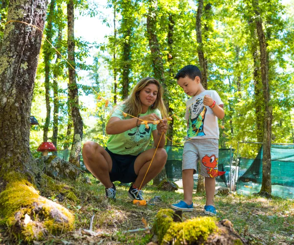 Woman and boy exploring a forest, examining something closely.