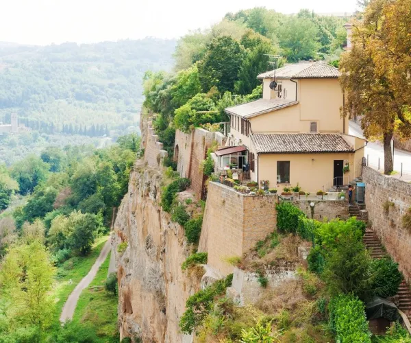 House perched on a lush cliffside, overlooking a green valley.