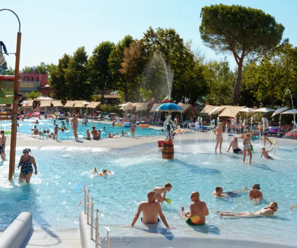 Crowded outdoor pool with people swimming and relaxing under a sunny sky.