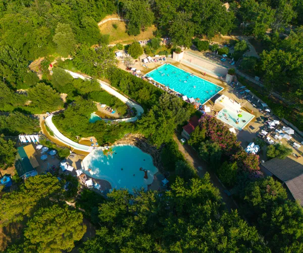 Aerial view of a lush water park with pools and slides surrounded by trees.